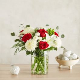 Red roses and white flowers arranged in a clear glass vase