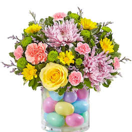 Mixed bouquet in a clear vase filled with pastel eggs