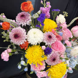 Mixed bouquet of pink, yellow, white, and purple flowers in a vase