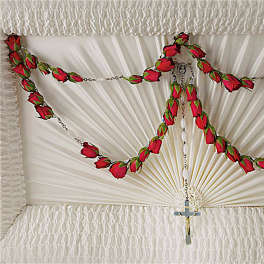 White casket spray with red rose garlands and a cross pendant