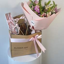 Pink bouquet in a gift box with a glass and baked treat