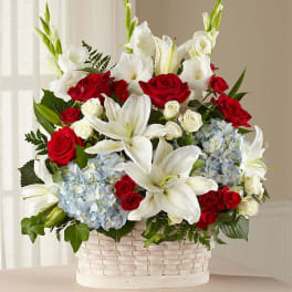 Red roses and white lilies in a white basket with blue hydrangeas