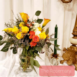 Bouquet of yellow and orange roses with calla lilies in a glass vase