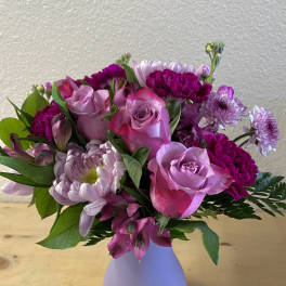 Pink and purple bouquet of roses and mums in a lavender vase