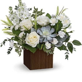 White roses and mixed white flowers in a wooden cube vase with a succulent