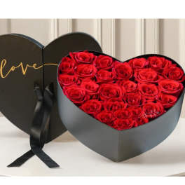 Heart-shaped box filled with red roses and a black ribbon
