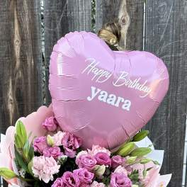Pink heart balloon above a bouquet of pink flowers