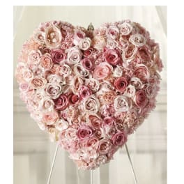 Heart-shaped arrangement of pink and blush roses on a stand
