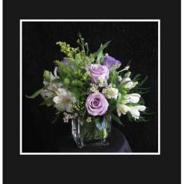 Lavender roses and white lilies in a clear glass vase