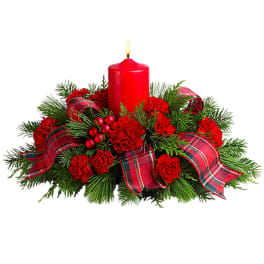 Red candle in a holiday arrangement with plaid ribbon and red flowers