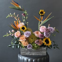 Mixed bouquet with sunflowers, roses, and bird of paradise in a wooden box