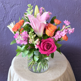 Pink lilies and roses arranged in a clear glass vase
