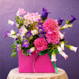 Pink and purple flowers arranged in a bright pink box
