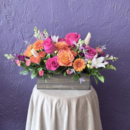 Mixed pink and orange flower arrangement in a wooden box