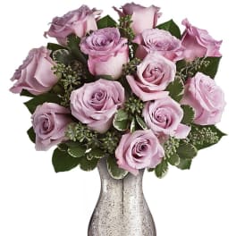 Arrangement of lavender roses in a speckled silver vase.