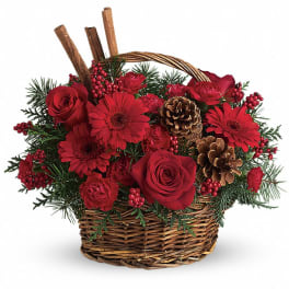 Red roses and gerbera daisies with pinecones and berries in a brown wicker basket