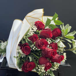 Bouquet of red roses with white filler flowers and white-gold wrapping