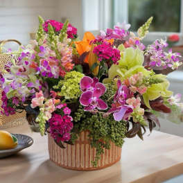 Mixed orchid and snapdragon arrangement in a striped ceramic vase
