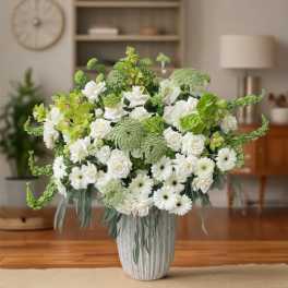 White and green floral arrangement in a ribbed vase