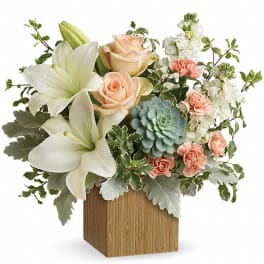 Compact arrangement of white lilies, peach roses, carnations and succulent in a wooden cube