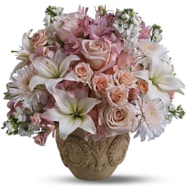 Pastel arrangement of pink roses, white lilies, and daisies in an ornate beige ceramic pot