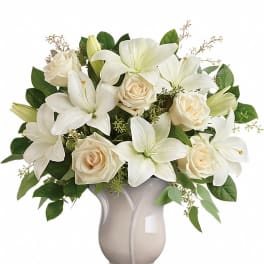 Arrangement of white lilies and cream roses in a pale pedestal vase