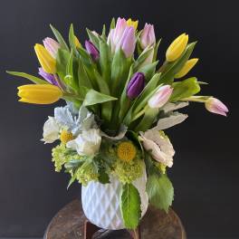Bouquet of yellow, pink, and purple tulips in a white vase