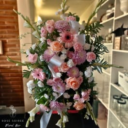 Pink and peach floral standing spray with white ribbon accents