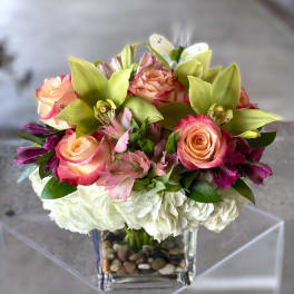 Bouquet of pink roses, orchids, and white hydrangeas in a glass vase