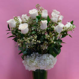 White roses and hydrangeas in a tall glass vase