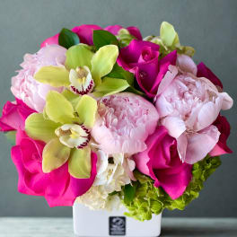 Pink and lime floral arrangement in a white square vase