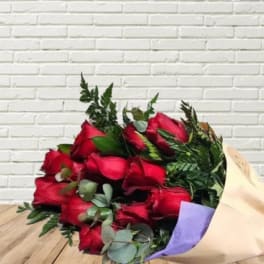 Bouquet of red roses wrapped in cream paper with a red ribbon