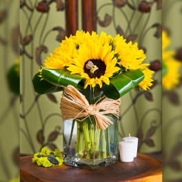 Sunflower arrangement in a glass vase with a raffia bow