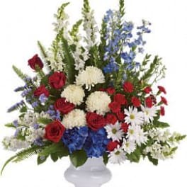 Mixed red, white, and blue floral arrangement in a white vase