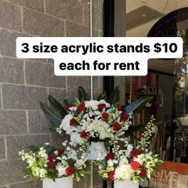 Three floral arrangements on clear acrylic stands with red and white flowers