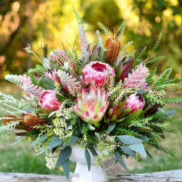 Pink protea bouquet in a white pedestal vase