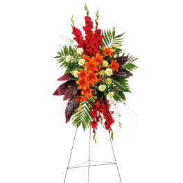 Tall standing floral spray with red and orange flowers on an easel