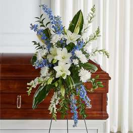 White lilies and blue flowers arranged on a casket