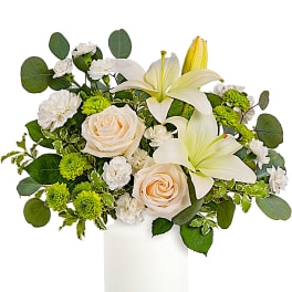 White lilies and cream roses in a white vase with green accents