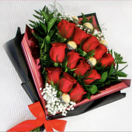 Bouquet of red roses with gold-wrapped chocolates and white filler flowers