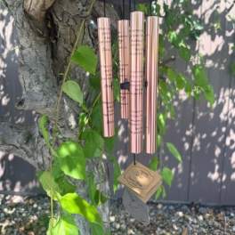 Rose-gold wind chime hanging from a tree branch