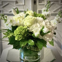 White and pale green floral arrangement in a glass vase