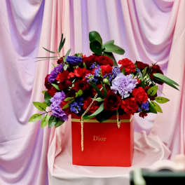 Red and purple flower arrangement in a red Dior box