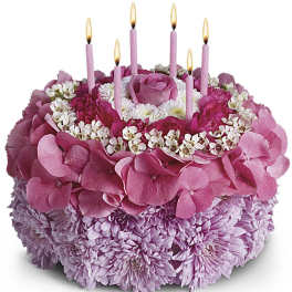 Pink floral cake with lit candles and a rose on top
