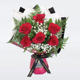 Bouquet of red roses with baby's breath and fern foliage in decorative wrapping