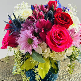 Mixed bouquet of red and pink roses with daisies in a blue vase