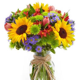 Bright mixed bouquet with sunflowers and purple asters in a clear glass vase