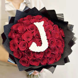 Bouquet of red roses wrapped in black paper with a white letter J