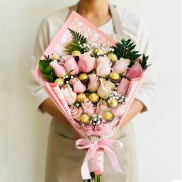 Pink rose bouquet with gold-wrapped chocolates and a pink ribbon