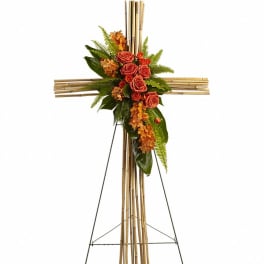 Standing bamboo cross with cluster of orange roses and orchids on a metal easel